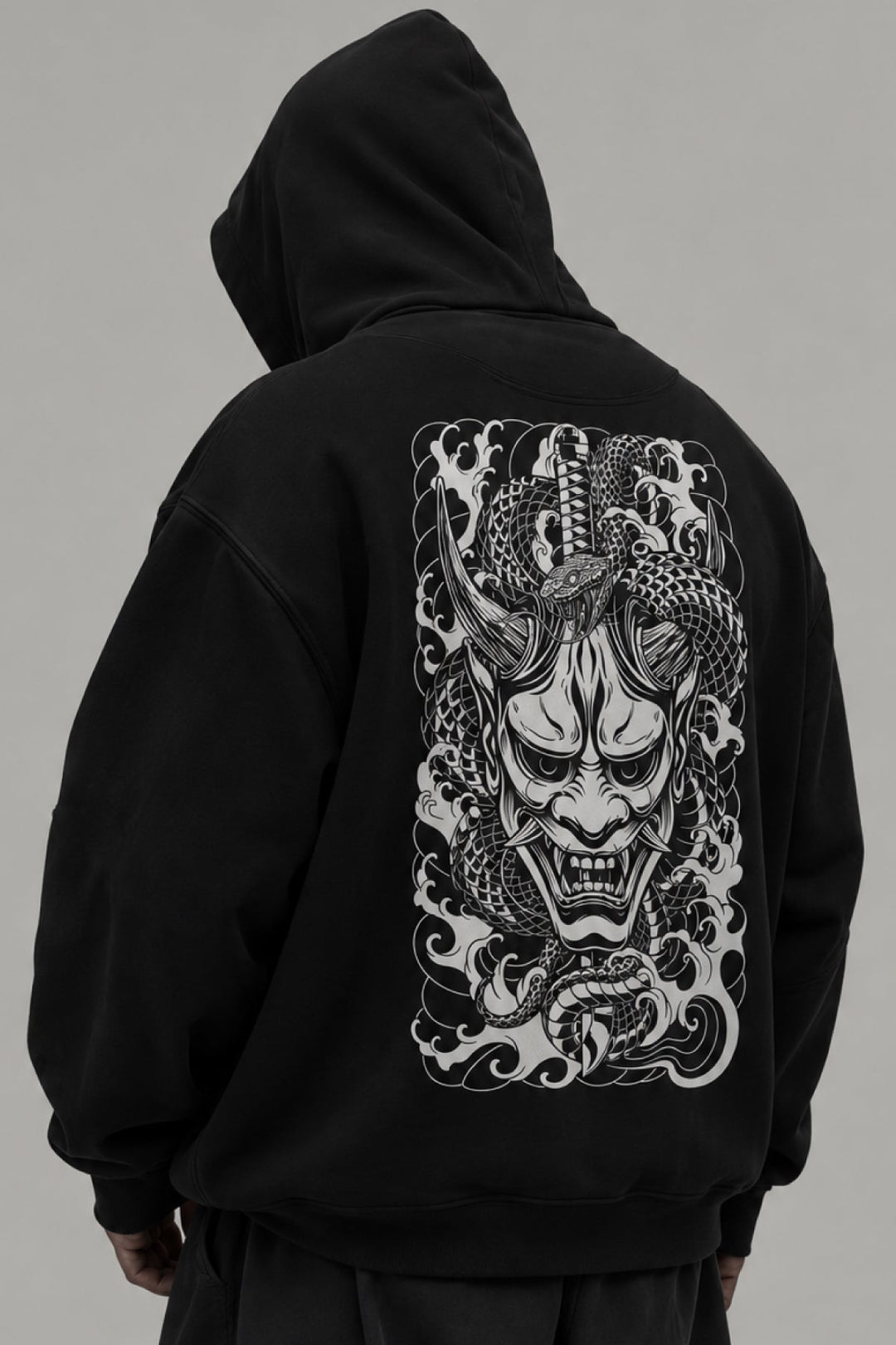Model wearing a black relaxed hoodie with a large Japanese oni mask, snake and sword back print