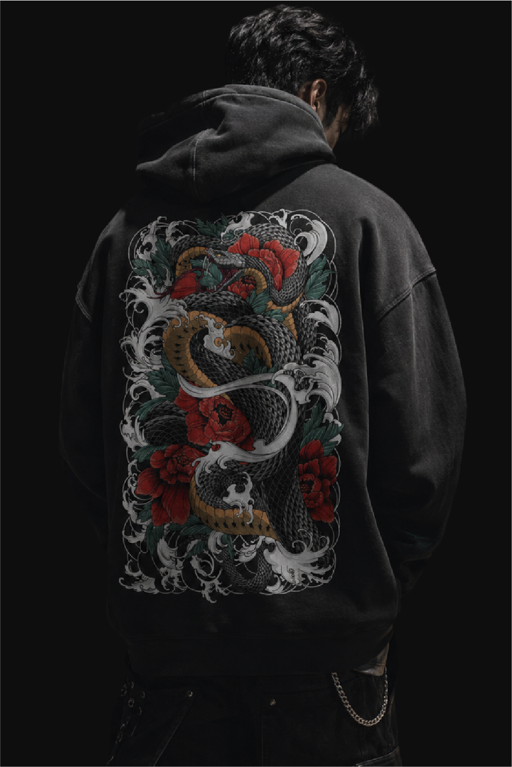 Man wearing a black hoodie with a large Irezumi inspired snake, wave and red flower back print in a dark streetwear style.