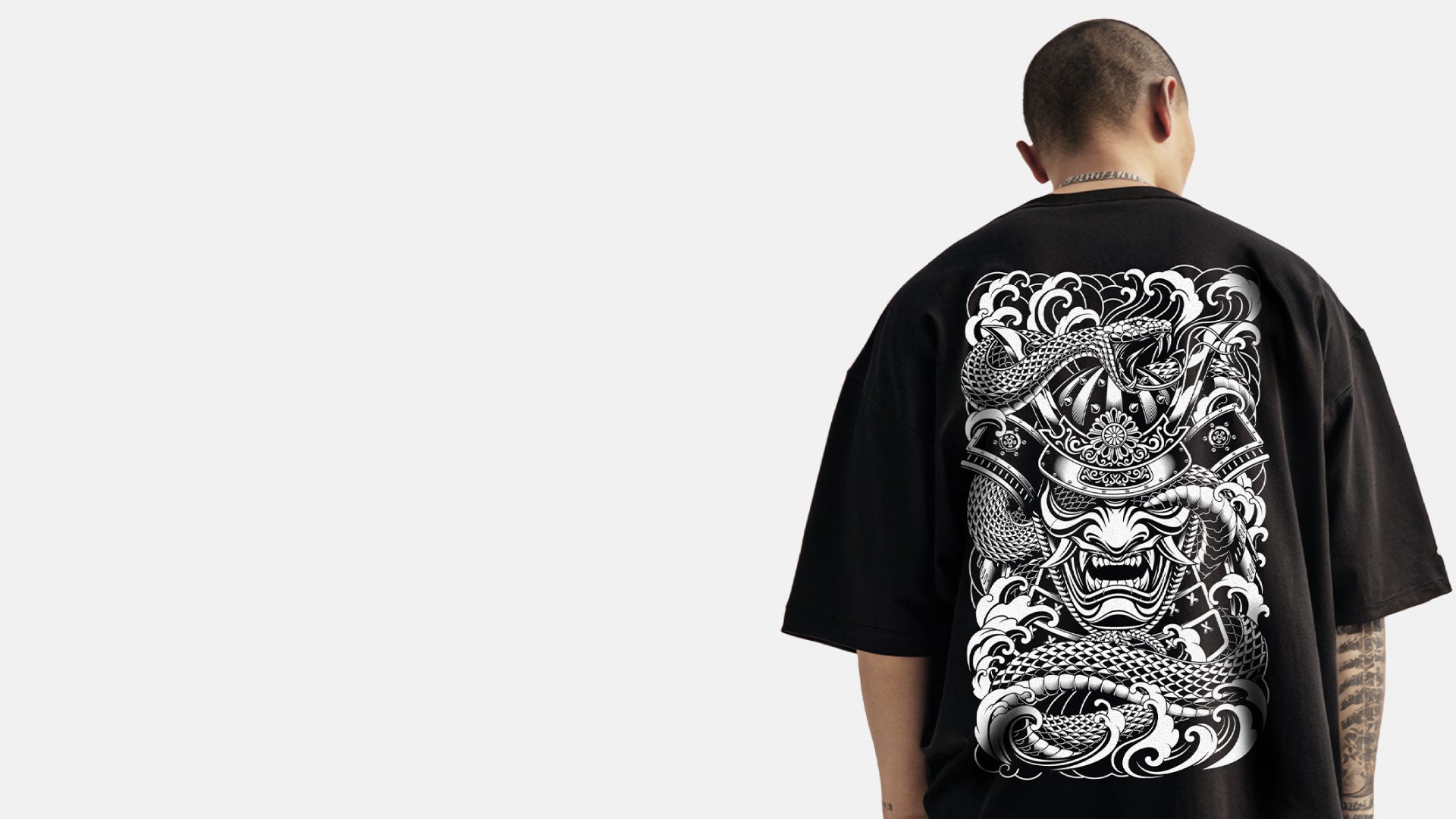 Person wearing a black t-shirt with a white Irezumi inspired samurai and snake design large on the back.