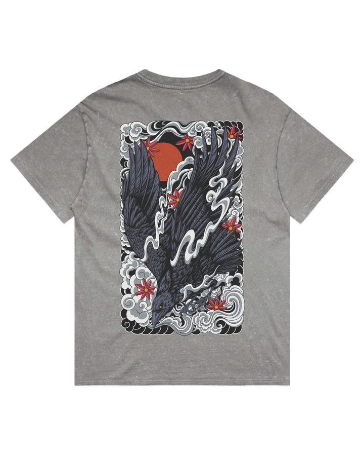 A grey stone wash short-sleeve t-shirt shown flat against a white background, featuring a large graphic print on the back with a black raven, red sun, and red flowers amidst white waves.