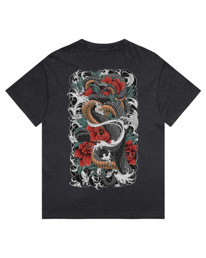 A black stonewash t-shirt featuring a large, detailed graphic print on the front. The graphic depicts a traditional Japanese tattoo style design with a black and white snake, red roses, and green leaves.